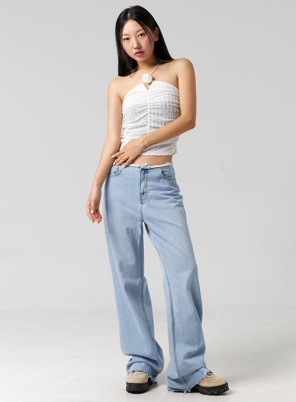 LEWKIN Cut Waist Wide Leg Jeans CG323 in light blue, full-length front shot on model, wide-fit cotton denim with frayed cut waist detail, paired with white halter crop top and chunky sneakers.