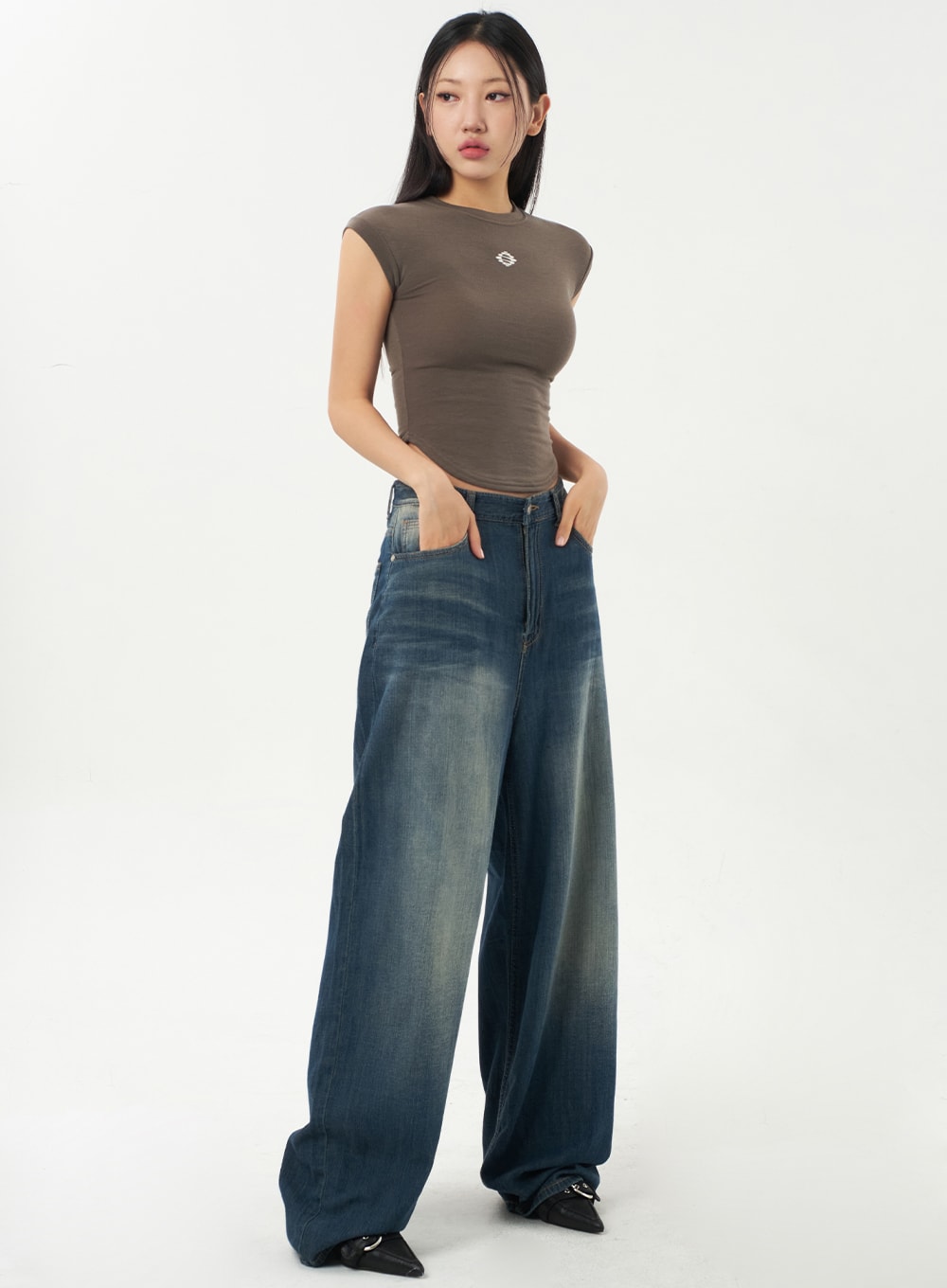 LEWKIN Baggy Low Rise Jeans CA326 in dark blue, three-quarter front view on model, wide-leg cotton denim with vintage wash, low waist, paired with brown crop top and black heels.
