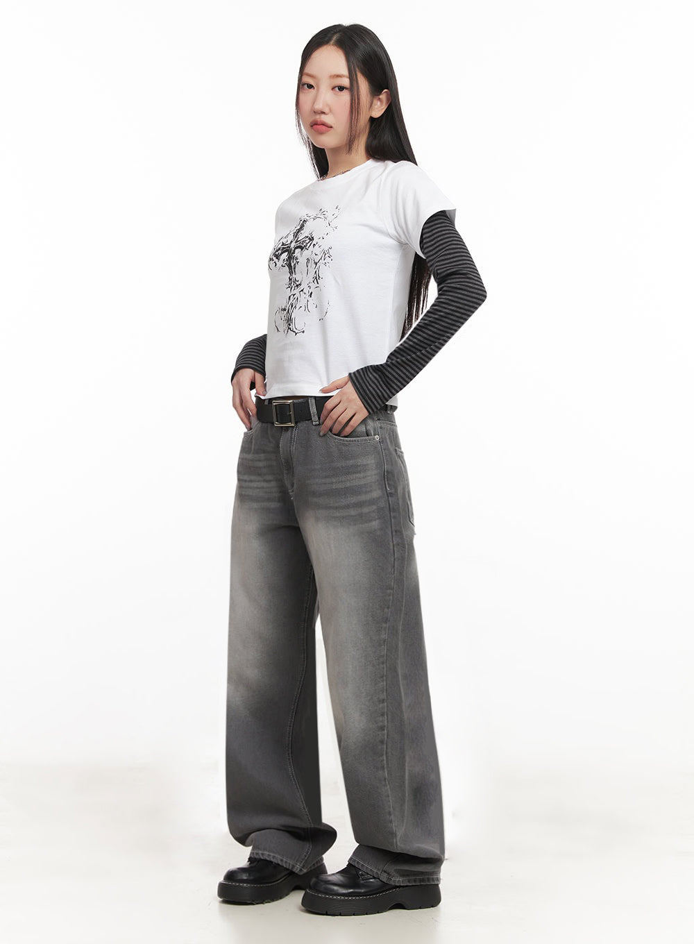 LEWKIN Becca Washed Straight-Leg Jeans IM524 in grey, 3/4 front view on model, wide-fit washed denim with belt, pooling hem, paired with layered graphic tee and chunky loafers.