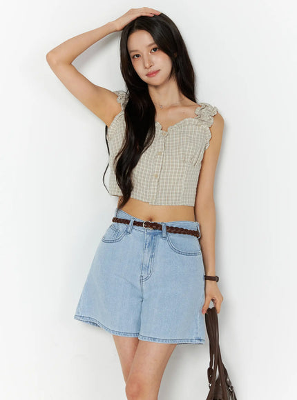 LEWKIN Plaid Ruffle Sleeveless Top CU522 in beige, front 3/4 view on model, plaid crop top with ruffle straps and button front, styled with light blue denim shorts and braided belt.