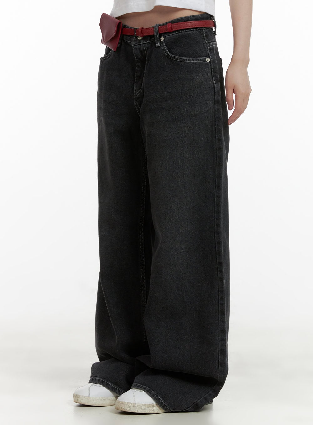 LEWKIN Low Rise Baggy Jeans CU410 in black, side close-up on model, wide-fit washed denim with low waist, styled with red belt bag and white sneakers.