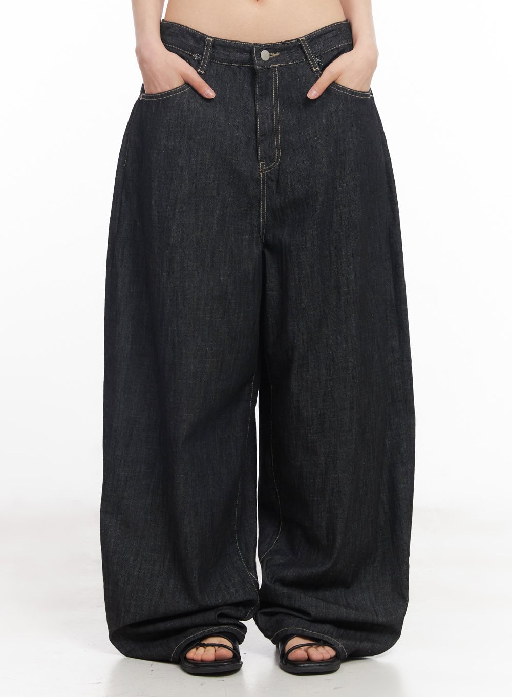 LEWKIN Elvie Baggy Jeans CY528 in black, front close-up on model, hands in pockets, ultra-wide cotton denim leg with contrast stitching, paired with black sandals.