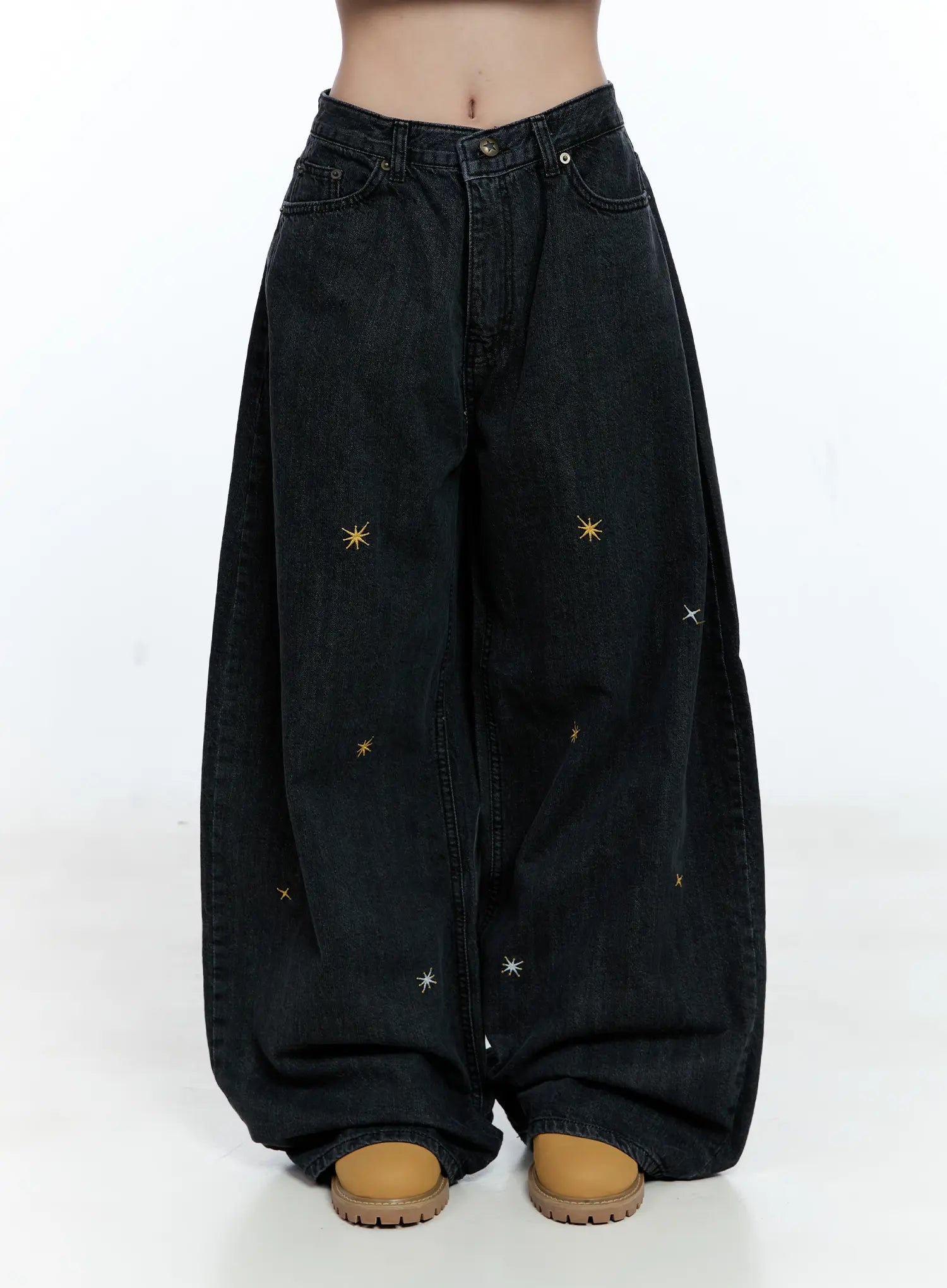 LEWKIN Wynter Star Embroidered Denim Jeans CG507 in black, front view on model cropped at waist, wide-leg cotton denim with scattered gold and silver star embroidery, worn with tan chunky shoes.