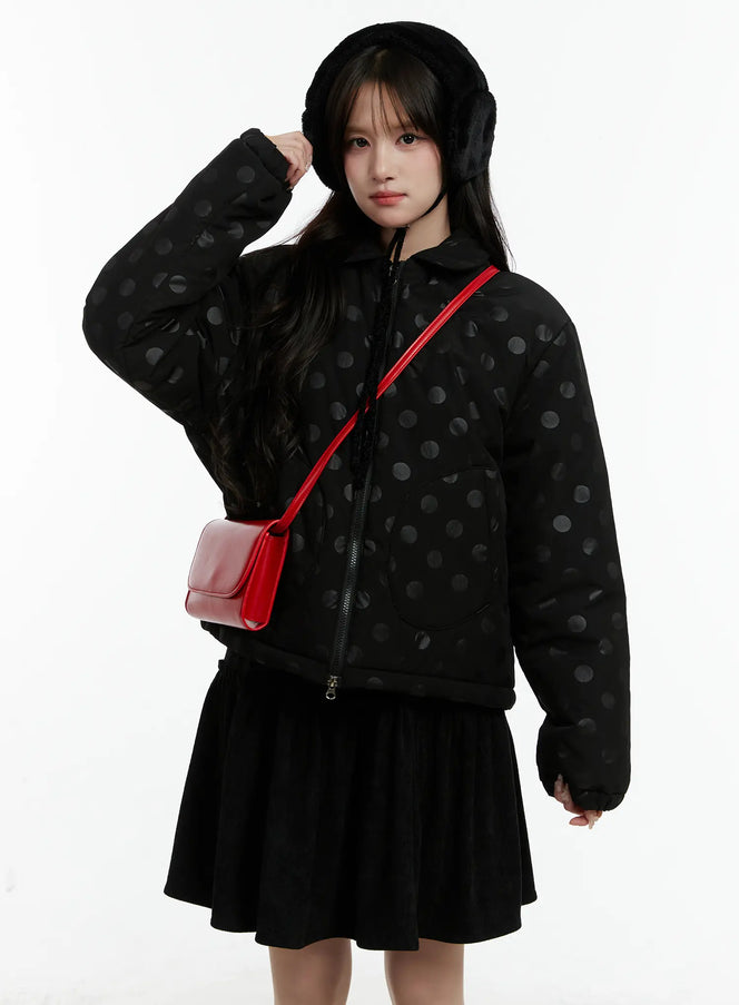 LEWKIN Polka Dot Bomber Jacket CD514 in black, front three-quarter shot on model wearing fur earmuffs, zip-up polyester with tonal dot pattern, paired with black mini skirt and red crossbody bag.