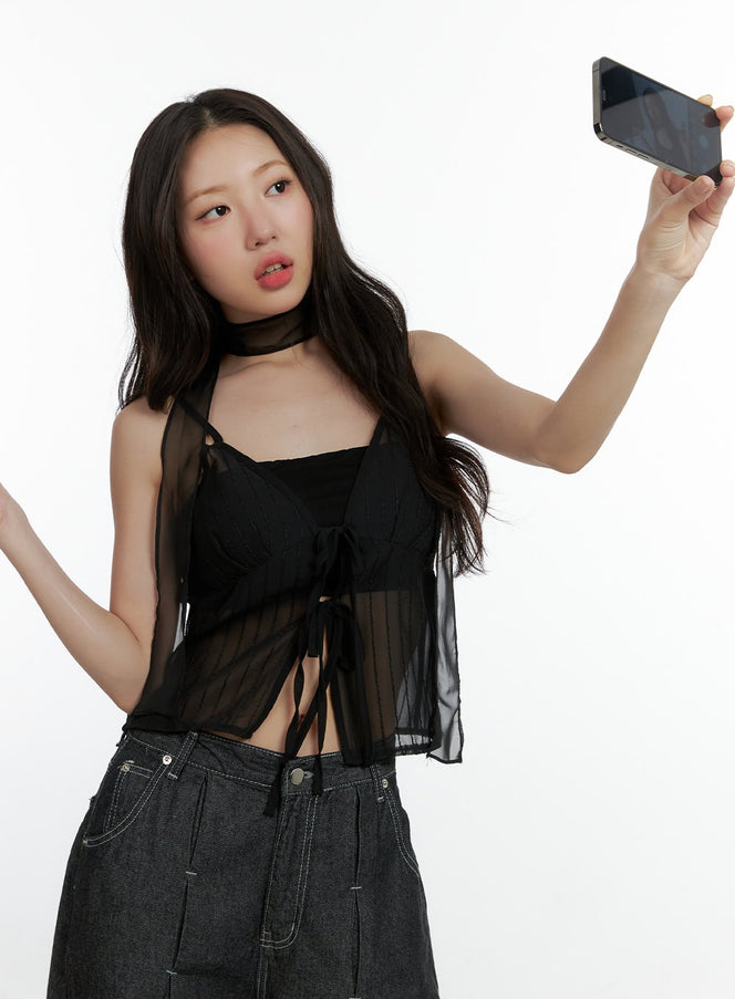 LEWKIN Mesh Slit Strap Tank Top with Scarf Set CL410 in black, front shot on model holding phone, sheer see-through mesh overlay with tie-front detail and scarf choker, paired with dark wide-leg jeans.