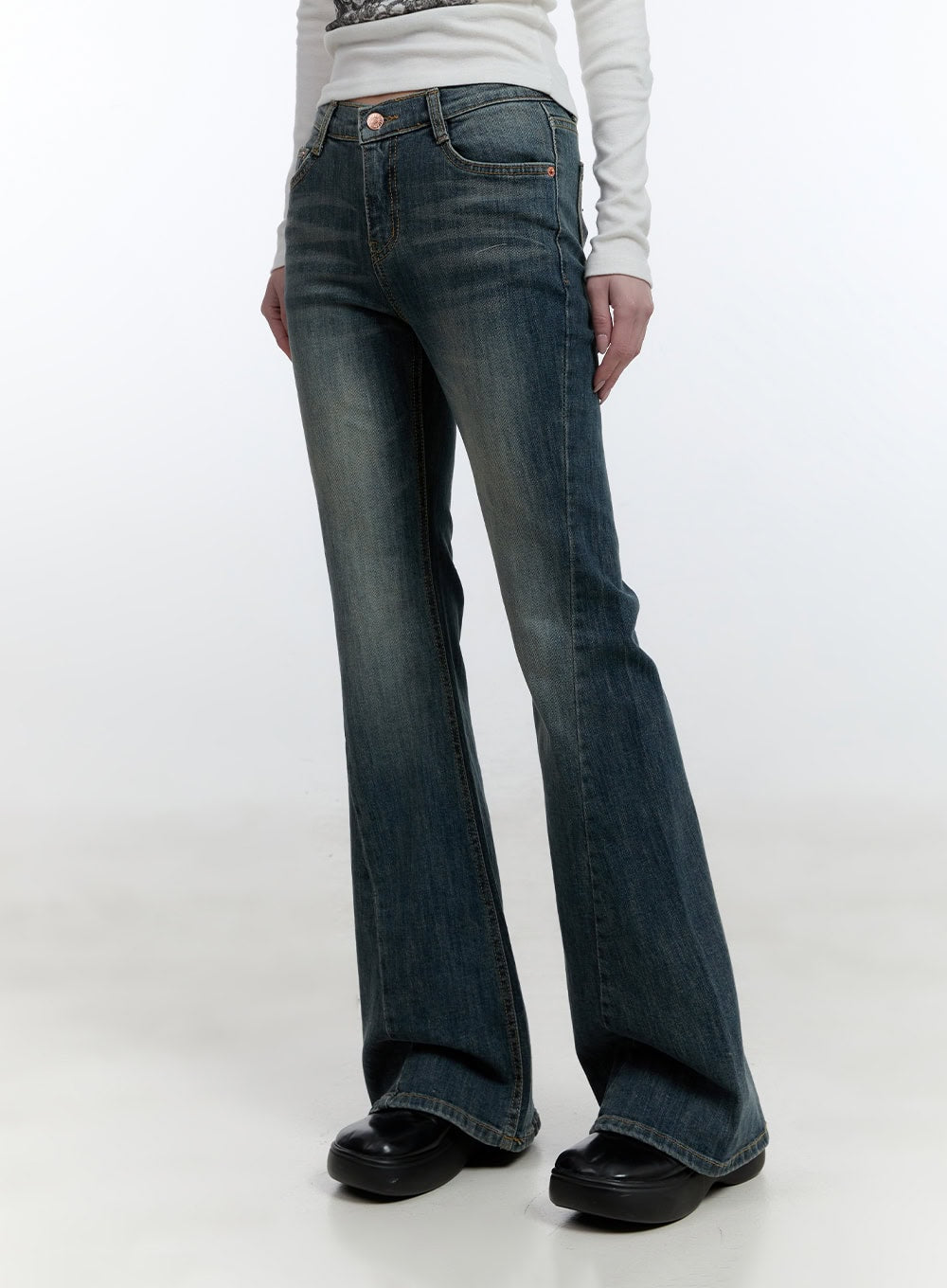 LEWKIN Mallory Skinny Bootcut Jeans CJ520 in blue, angled front view on model, slim-fit washed denim with bootcut flare hem, paired with white long-sleeve top and black platform shoes.