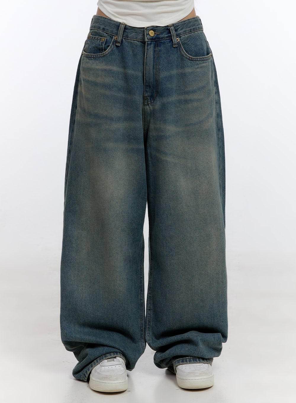 LEWKIN Zola Casual Fit Denim Jeans CO422 in blue, front close-up on model, wide-fit baggy cotton denim with washed fading, gold button, five-pocket, pooling hem, white sneakers.