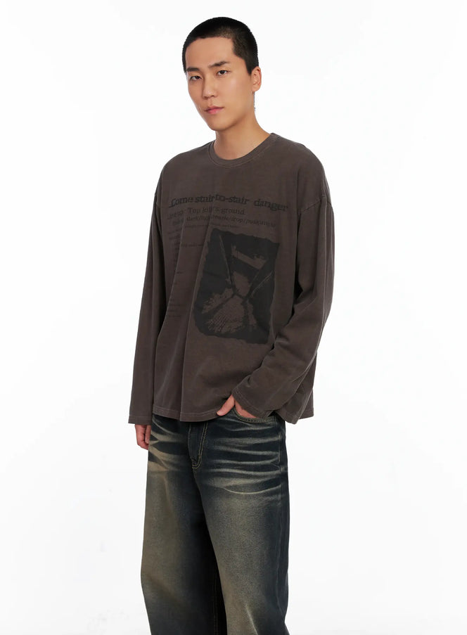 LEWKIN Men's Edgy Graphic Long Sleeve Tee IS509 in dark brown, angled front view on model, washed cotton oversize fit with stair-to-stair danger text and hourglass print, styled with vintage jeans.