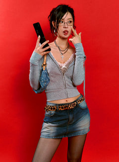 LEWKIN Slim Fit Zip-Up Hoodie CS510 in gray, front three-quarter editorial shot on model against red backdrop, slim long sleeve zip-up with hood down, layered over leopard lace cami, styled with denim mini skirt and leopard belt.