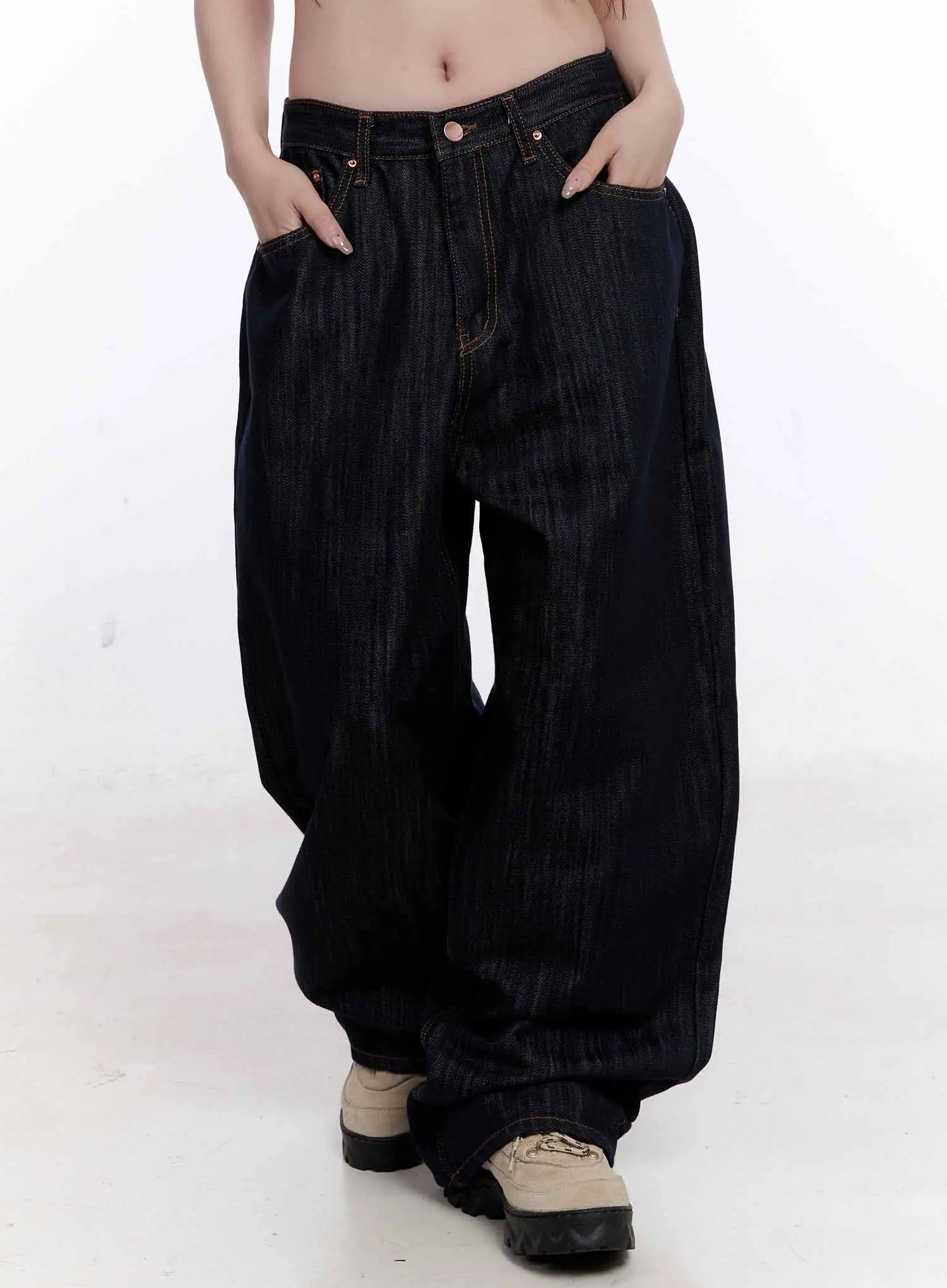 LEWKIN Haewon Dark Washed Baggy Jeans CS530 in dark blue, front crop view on model, hands in pockets, extreme oversize cotton denim with contrast amber stitching, paired with chunky sneakers.
