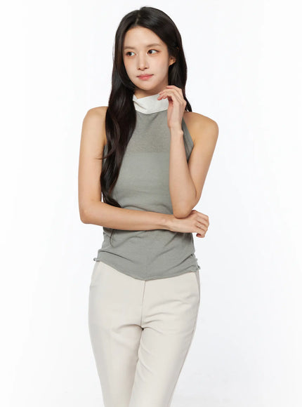 LEWKIN Neck-Tie Halter Top CU522 in dark green, front three-quarter crop on model, sleeveless halter with contrast cream neck-tie, fitted knit body, paired with cream flare trousers.