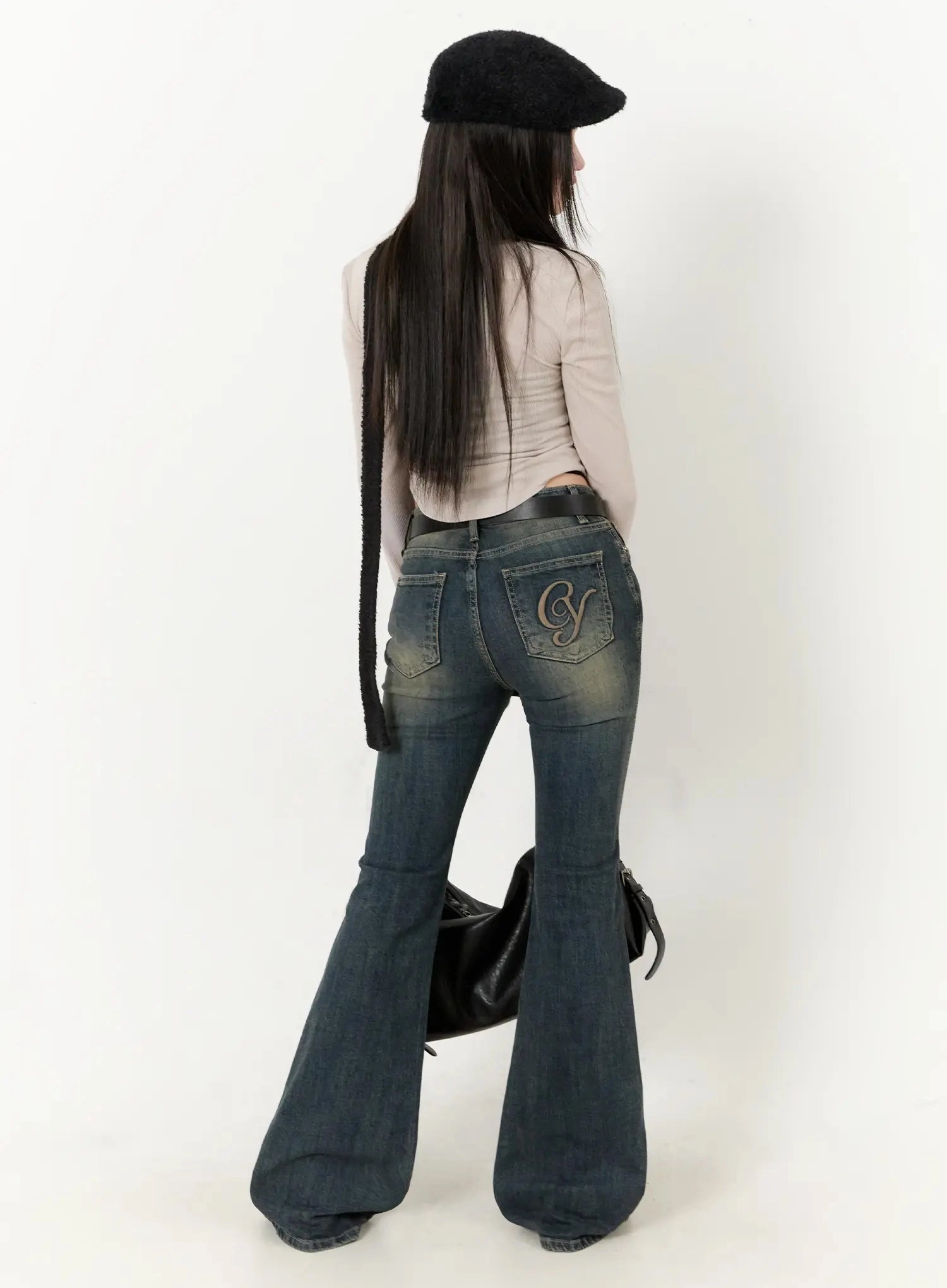 LEWKIN Karla Vintage Logo Hip Pad Flare Jeans IO520 in washed dark blue, back full-body on model, CY logo embroidery on rear pocket, paired with beige top and black beret.