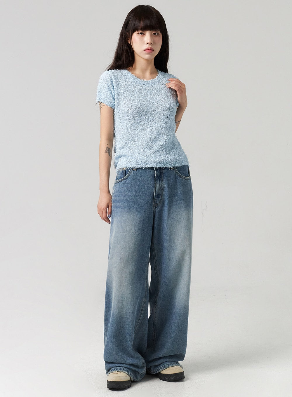 LEWKIN Baggy Jeans CL313 in washed blue, full-length front view on model, wide-leg cotton denim with faded wash, paired with light blue bouclé top and chunky sneakers.