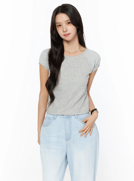 LEWKIN Polka Dot Striped Crop Tee CU522 in gray, front half-body shot on model, polka dot body with striped raglan sleeves, fitted crop silhouette, paired with light blue jeans.