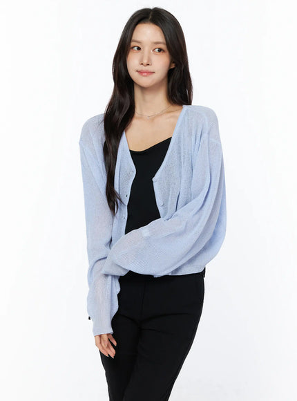 LEWKIN Sheer V-Neck Cardigan CU522 in light blue, three-quarter front view on model, semi-sheer open-knit with button front, layered over black cami and black trousers.
