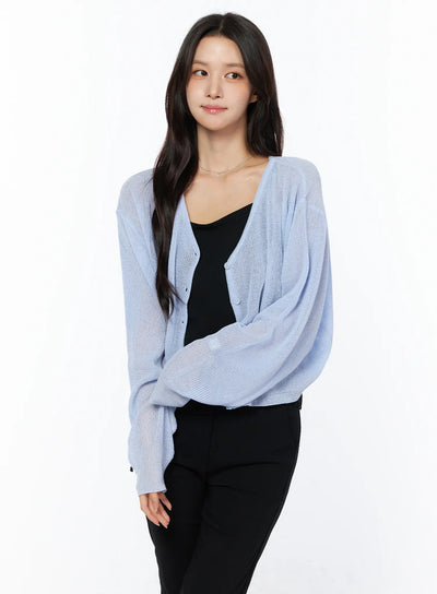 LEWKIN Sheer V-Neck Cardigan CU522 in light blue, three-quarter front view on model, semi-sheer open-knit with button front, layered over black cami and black trousers.