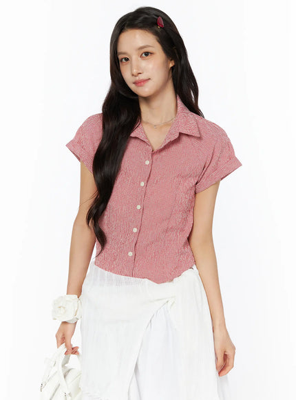 LEWKIN Gingham Button-Up Short Sleeve Blouse CU522 in red, three-quarter front view on model, cropped fit with point collar, pearl buttons, cuffed short sleeves, paired with white skirt.