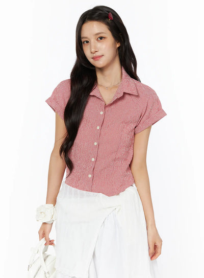 LEWKIN Gingham Button-Up Short Sleeve Blouse CU522 in red, three-quarter front view on model, cropped fit with point collar, pearl buttons, cuffed short sleeves, paired with white skirt.