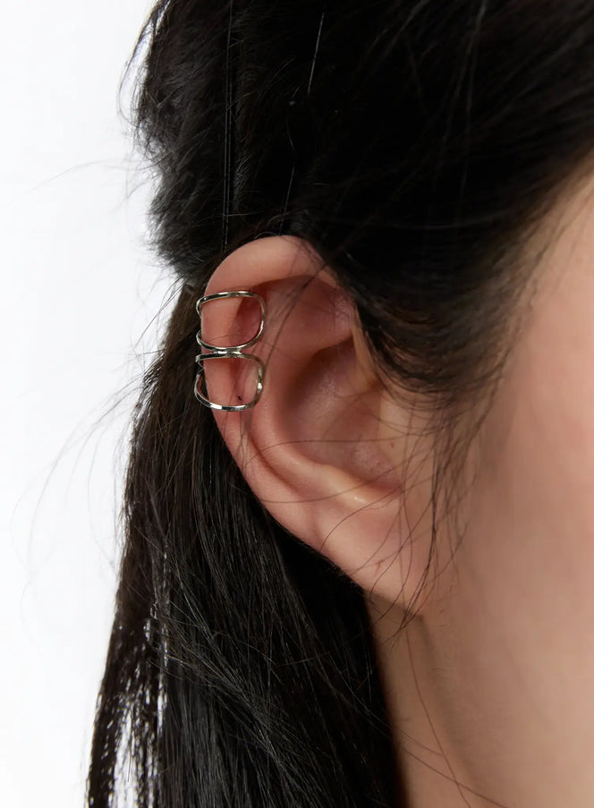 LEWKIN Double Swirl Ear Cuff CA508 in silver, close-up side view worn on model's ear, dual open-wire swirl design gripping the upper cartilage, no piercing needed.