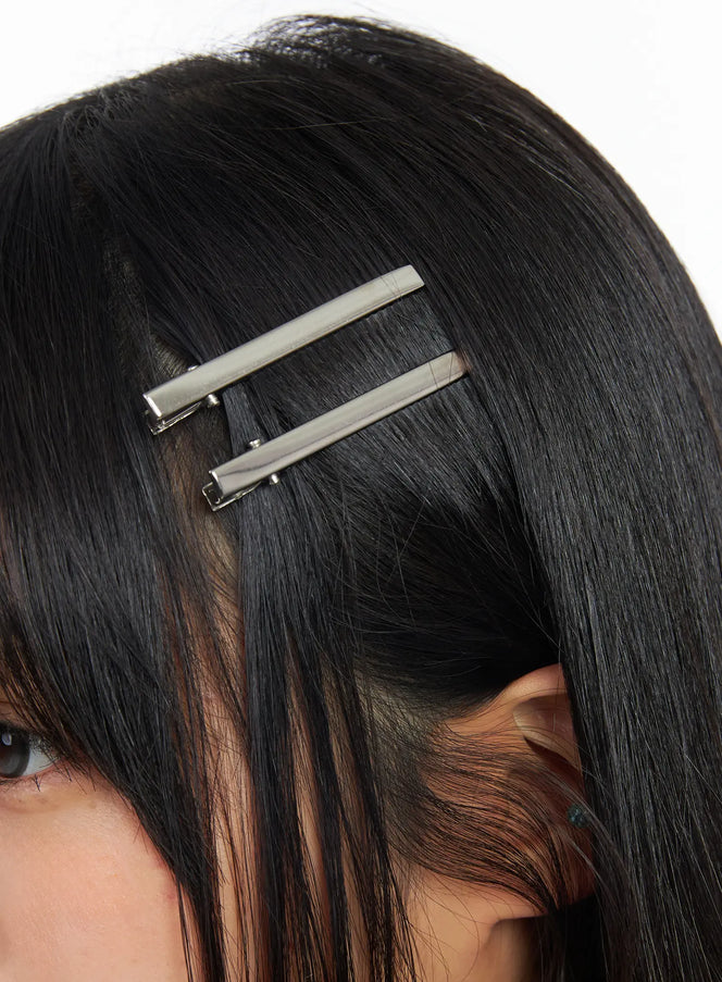 LEWKIN Sleek Hair Clip CF506 in silver, extreme close-up on model's temple, two slim metallic bar clips stacked parallel in straight black hair, minimal acubi style.