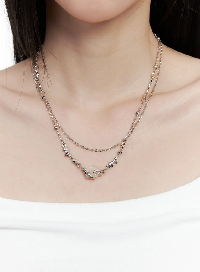 LEWKIN Donut Pendant Necklace CO503 in silver, close-up on model's neck, double-layer chain with donut pendant and bead accents, worn over white tank top.