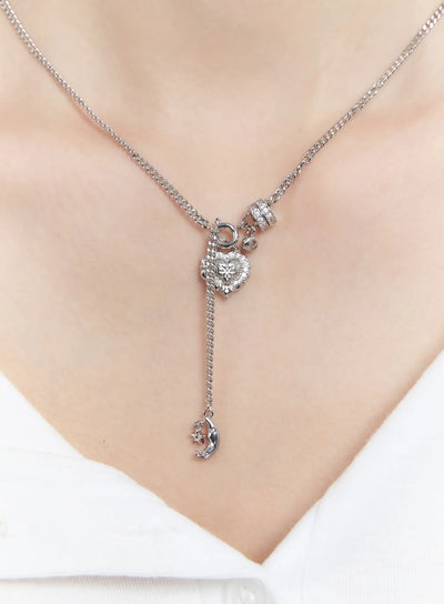 LEWKIN Two-way Heart Charm Necklace CM505 in silver, close-up on model's neck, crystal-encrusted heart charm with dangling moon and star pendant on curb chain.