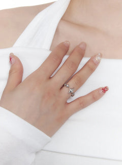 LEWKIN Star Open Ring CJ523 in silver, close-up worn on model's middle finger, star and moon charms with bead details, open adjustable band, styled with white top.