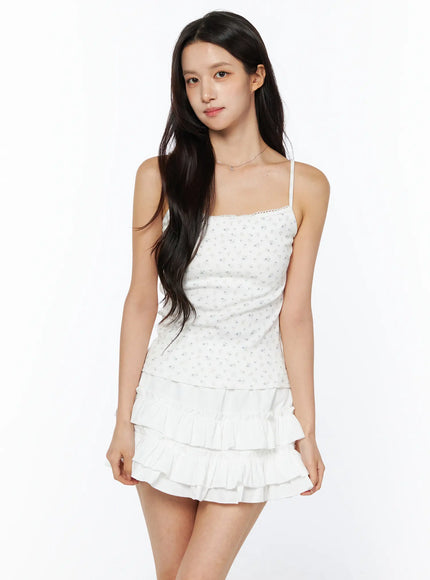 LEWKIN Floral Ribbed Cami Top CU522 in white, front 3/4 view on model, ditsy floral print with lace-trim neckline and thin straps, paired with white tiered ruffle mini skirt.