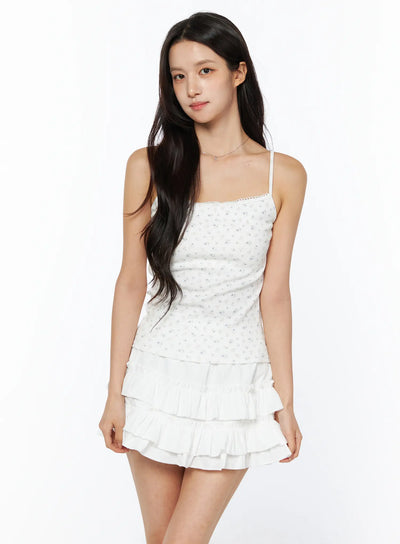 LEWKIN Floral Ribbed Cami Top CU522 in white, front 3/4 view on model, ditsy floral print with lace-trim neckline and thin straps, paired with white tiered ruffle mini skirt.