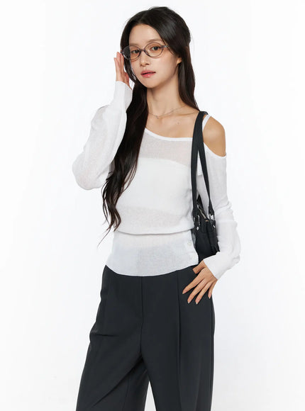 LEWKIN One-Shoulder Knit Top CU522 in white, front three-quarter view on model, sheer lightweight knit with one cold-shoulder strap detail, paired with black wide-leg trousers and crossbody bag.