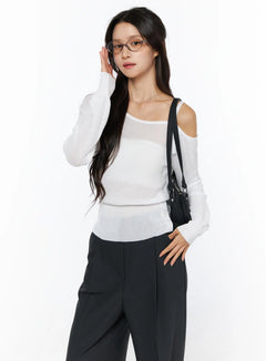 LEWKIN One-Shoulder Knit Top CU522 in white, front three-quarter view on model, sheer lightweight knit with one cold-shoulder strap detail, paired with black wide-leg trousers and crossbody bag.