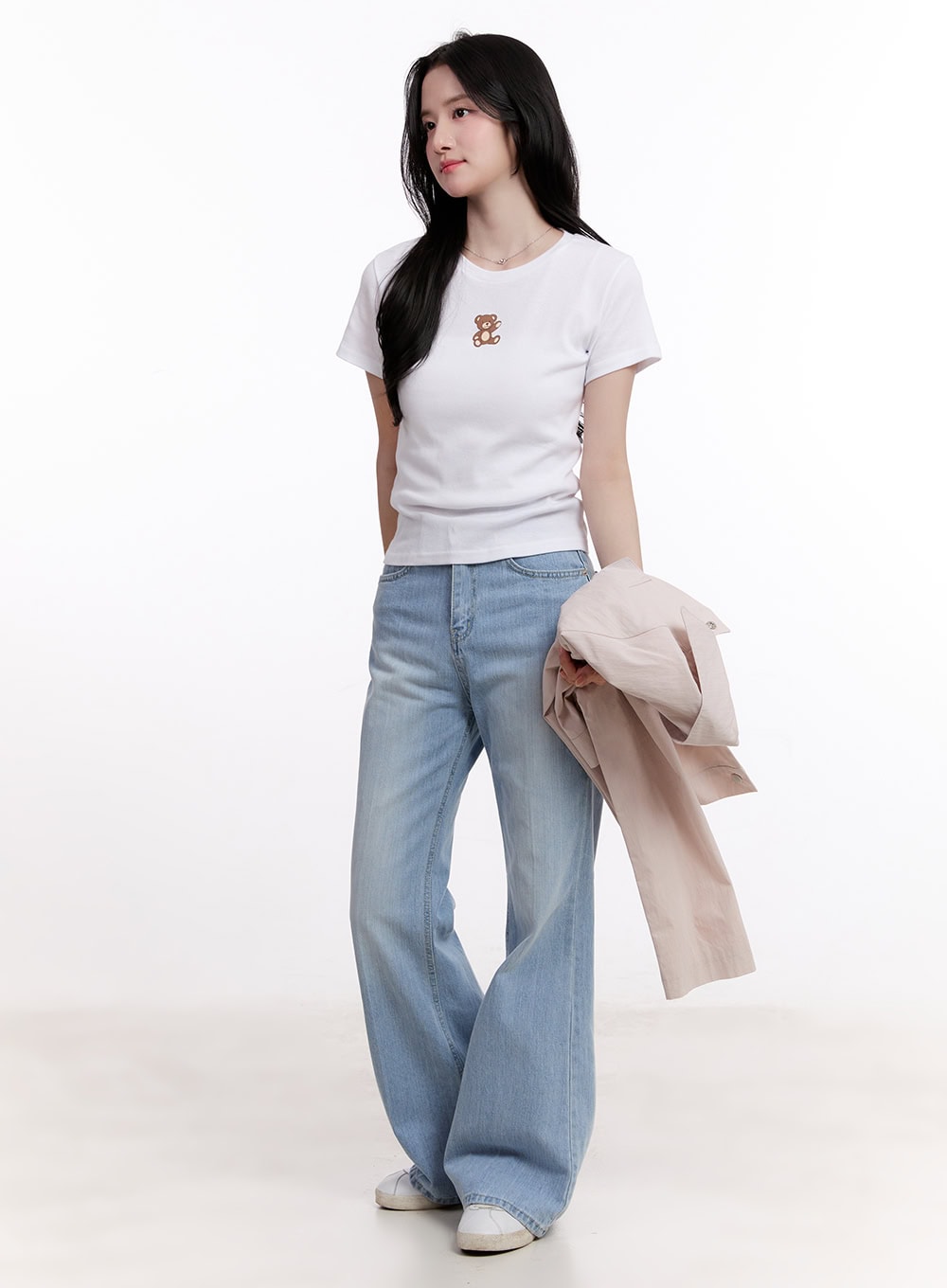 Daniella Relaxed-Fit Flared Jeans CM526 in light blue, full-body front styling shot, model holding beige jacket, paired with white graphic tee and white sneakers.