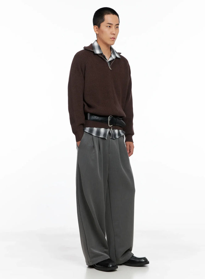 Men's Knit Zip-Up Sweater IS502 in Brown, three-quarter side view on model, relaxed ribbed knit silhouette styled with plaid shirt, black leather belt, and wide-leg grey trousers with loafers.