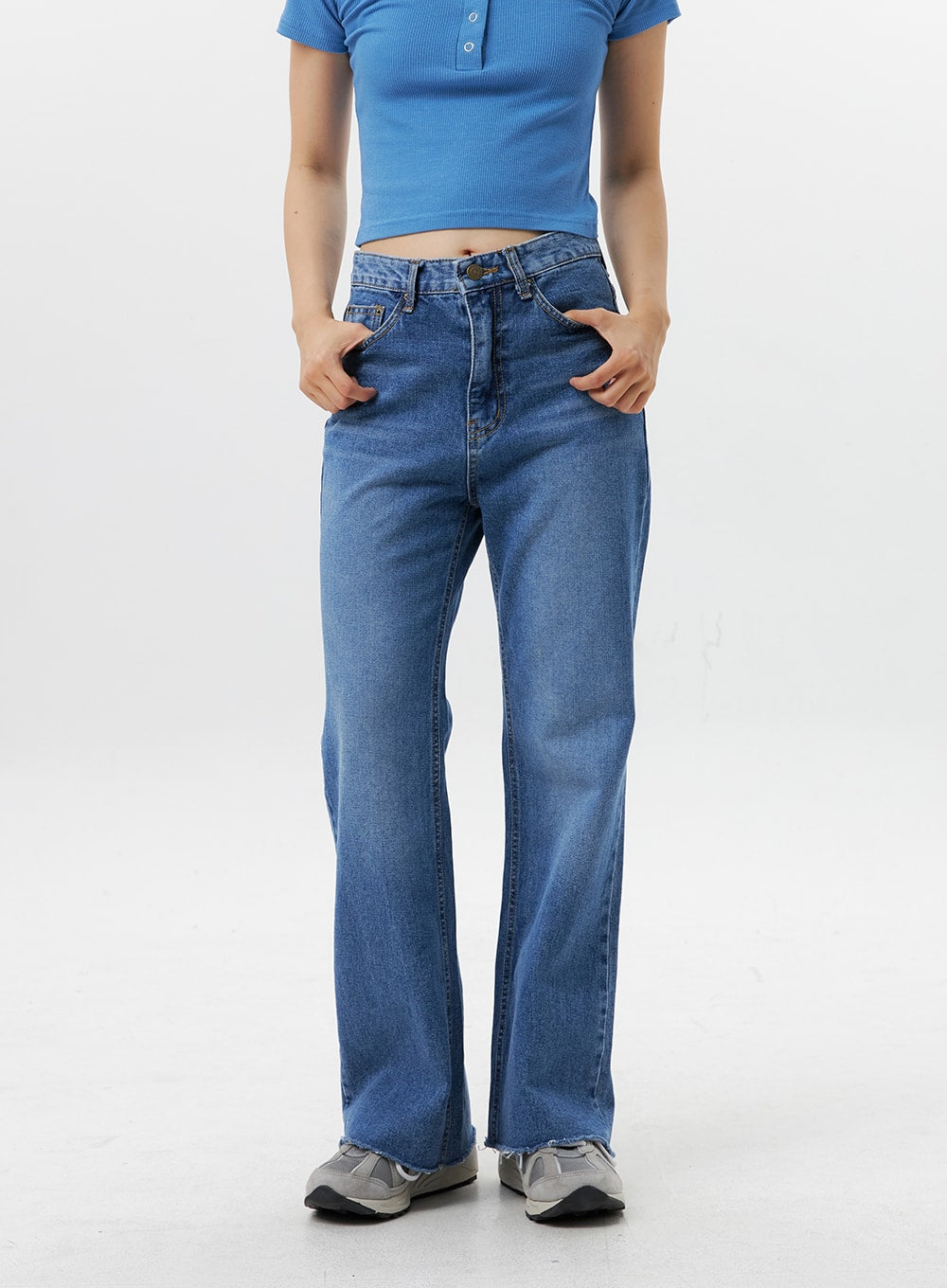 Straight-Leg Jeans OG318 in medium blue, front waist-to-hem close-up on model, high-rise 5-pocket denim, straight silhouette with subtle flare, raw frayed hem, hands in pockets.