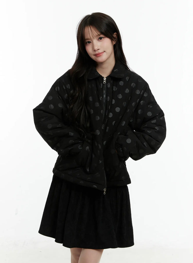 Polka Dot Bomber Jacket CD514 in black, front full-body shot on model, loose fit zip-up with collar and large tonal polka dot print, styled over black mini skirt.