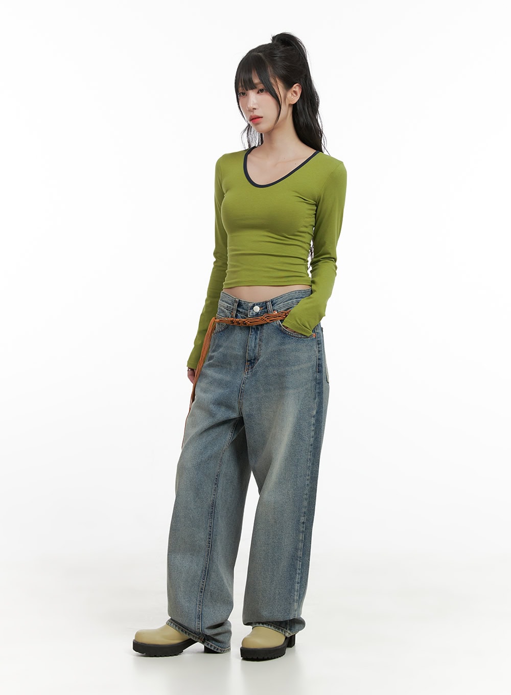 Millie Washed Baggy Jeans CG421 in Blue, full-body front shot on model, wide-leg washed denim with braided belt, styled with green long-sleeve crop top and olive chunky boots.