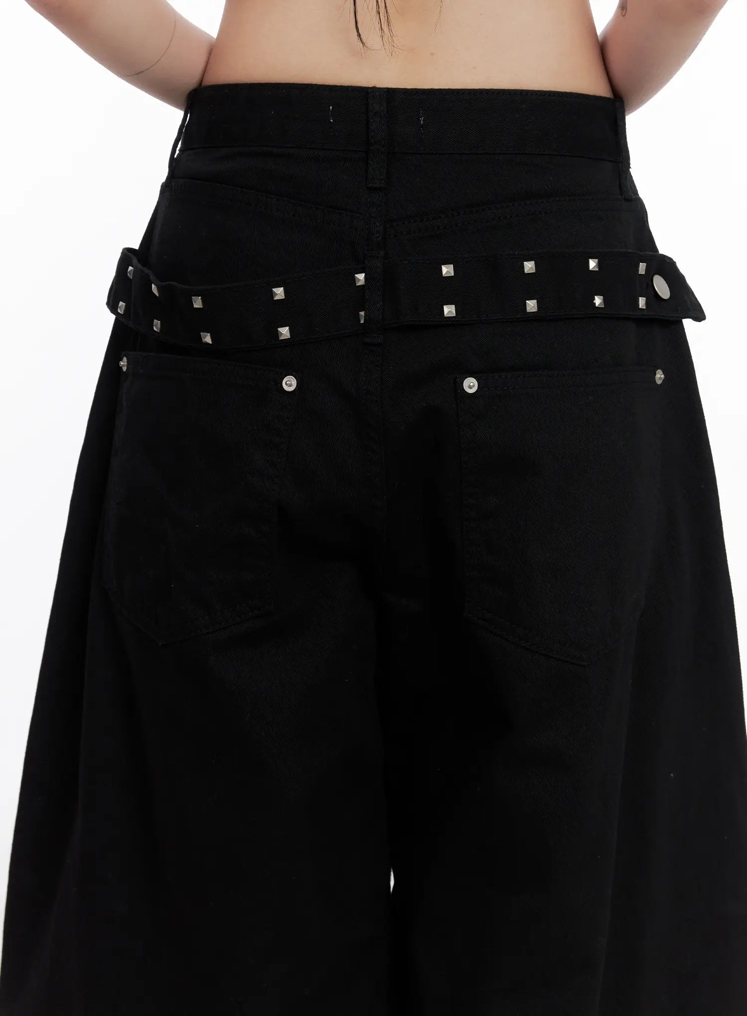 Nana Studded Belt Balloon Jeans CS512 in black, back close-up on model, silver square-stud belt detail across waistband, back pockets and buckle clasp visible.
