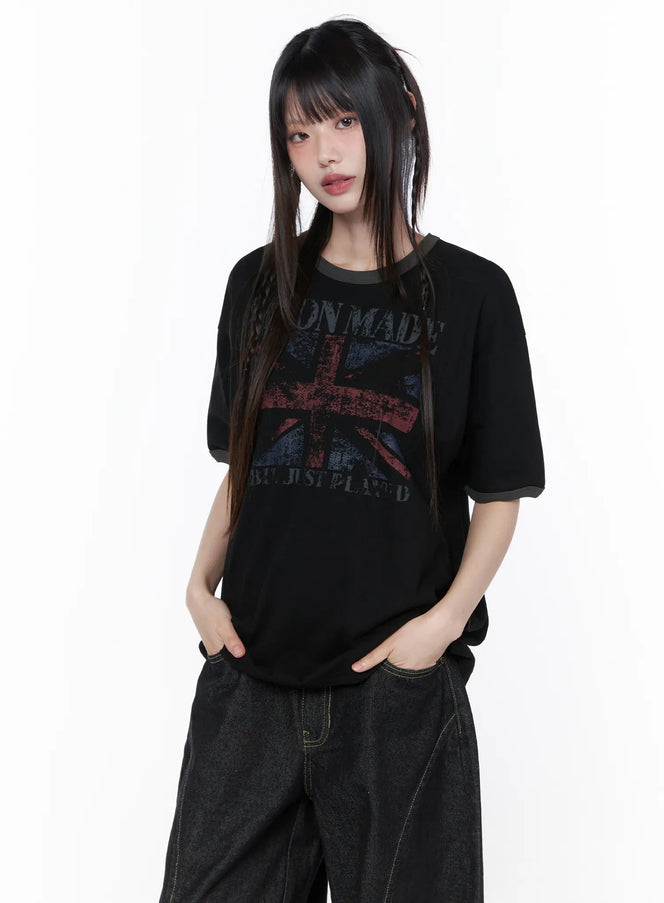 Graphic Short Sleeve Tee CU519 in black, front view on model standing, faded Union Jack graphic with contrast gray ringer collar, paired with dark baggy denim.