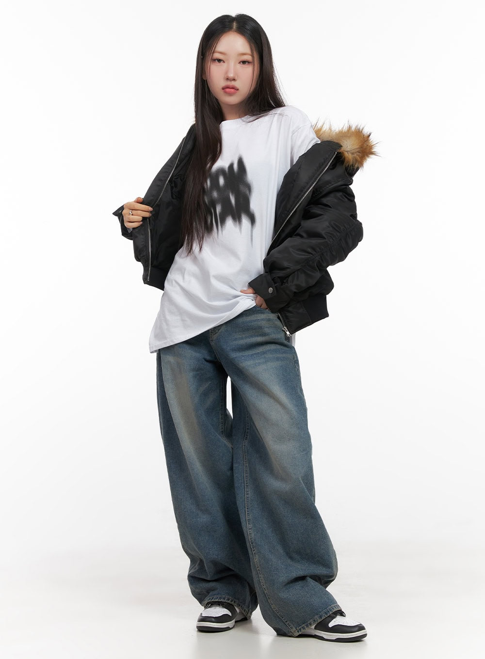 Mikaela Comfy Baggy Jeans CD411 in blue, full-body front shot on model, wide-fit washed denim pooling at hem, styled with graphic tee and fur-trim bomber jacket and sneakers.