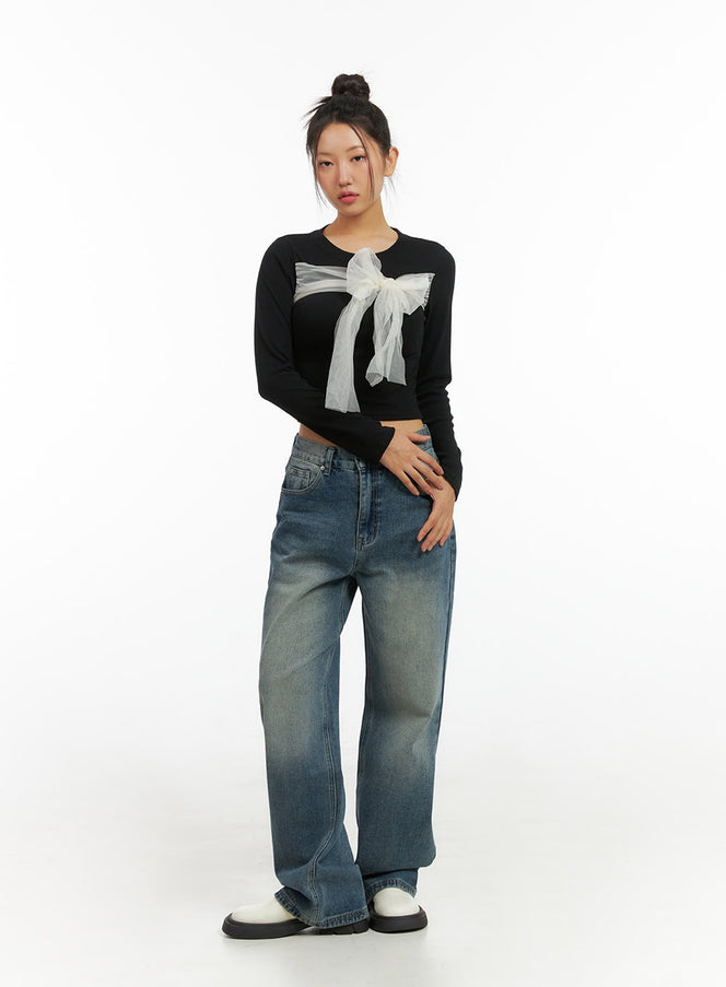 Ribbon Tied Long Sleeve Top IS402 in black, full-body front shot on model, slim crop length with oversized tulle ribbon, styled with wide-leg washed jeans and white loafers.