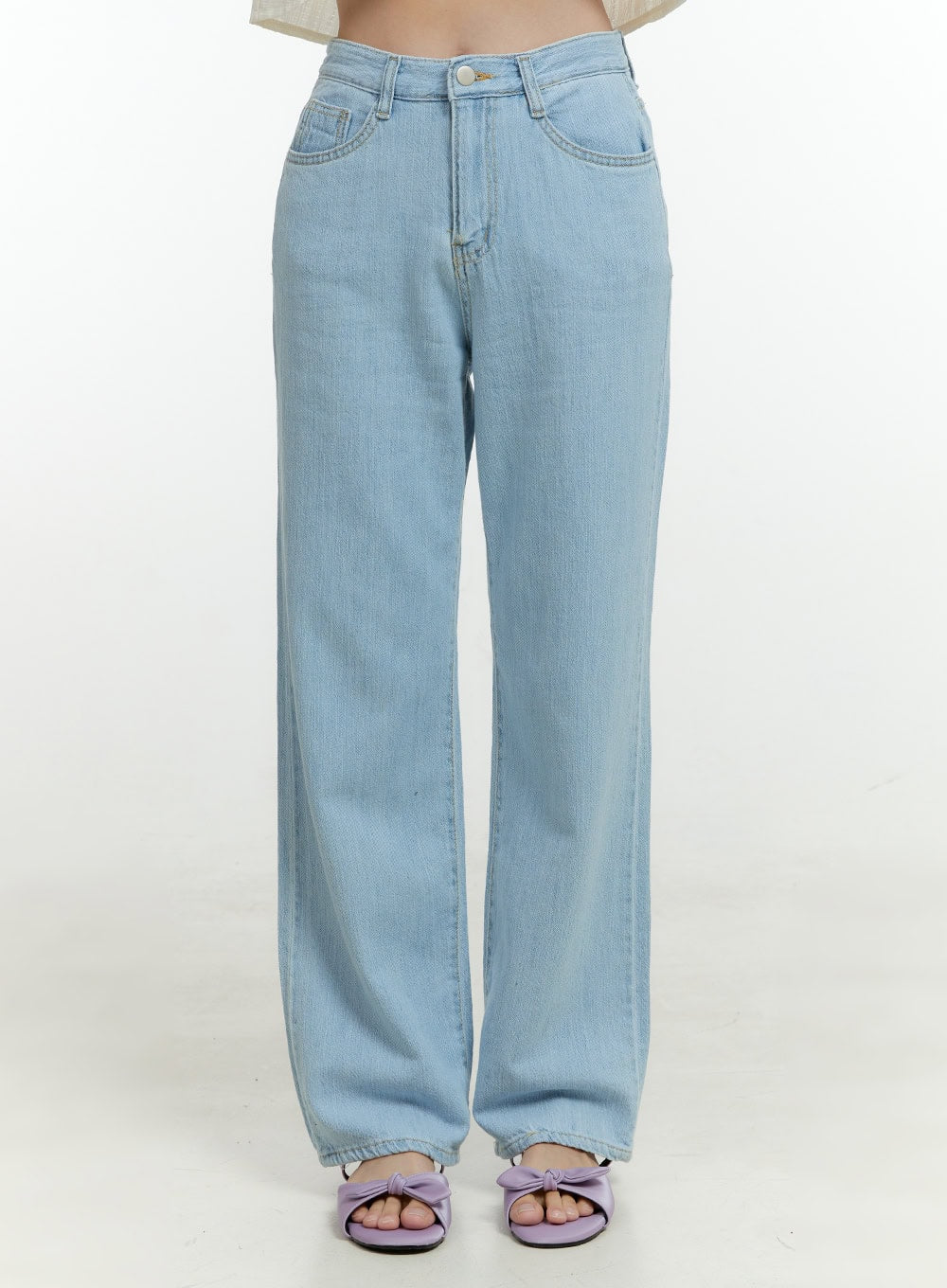 Ava Light Washed Straight Jeans OL430 in light blue, front cropped shot on model, high-rise waistband with gold button, wide straight leg, five-pocket denim, paired with lavender bow sandals.