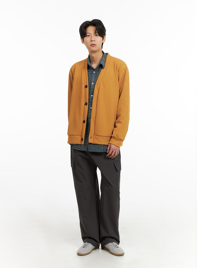 Men's V-Neck Buttoned Sweater IA402 in dark yellow, full-body front shot on model, relaxed fit ribbed knit, styled over plaid shirt with dark cargo pants and sneakers.
