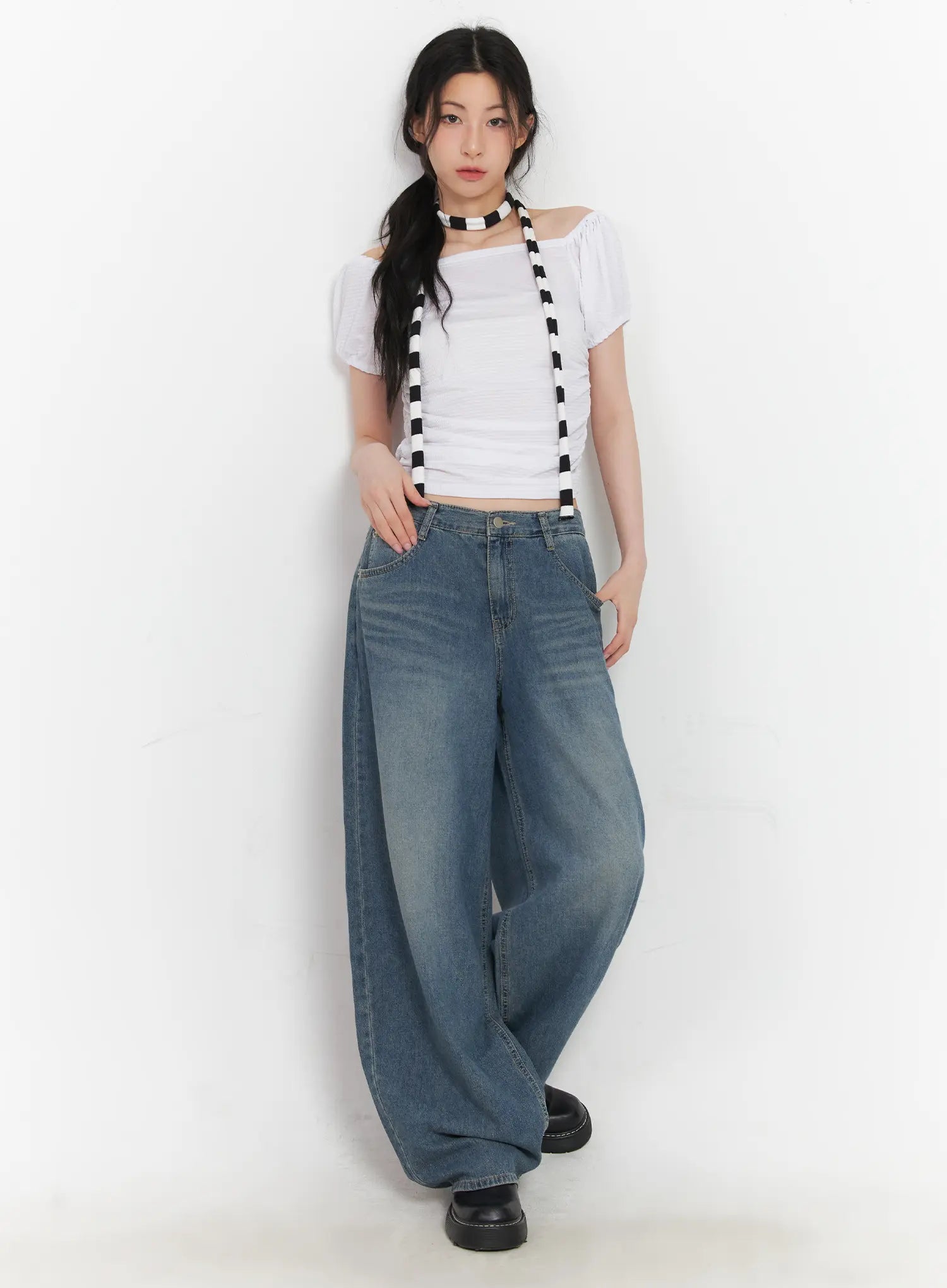 Chaewon Washed Wide-Leg Jeans CU511 in blue, full-body front on model leaning against wall, styled with white crop top and black-white striped suspender accessory.