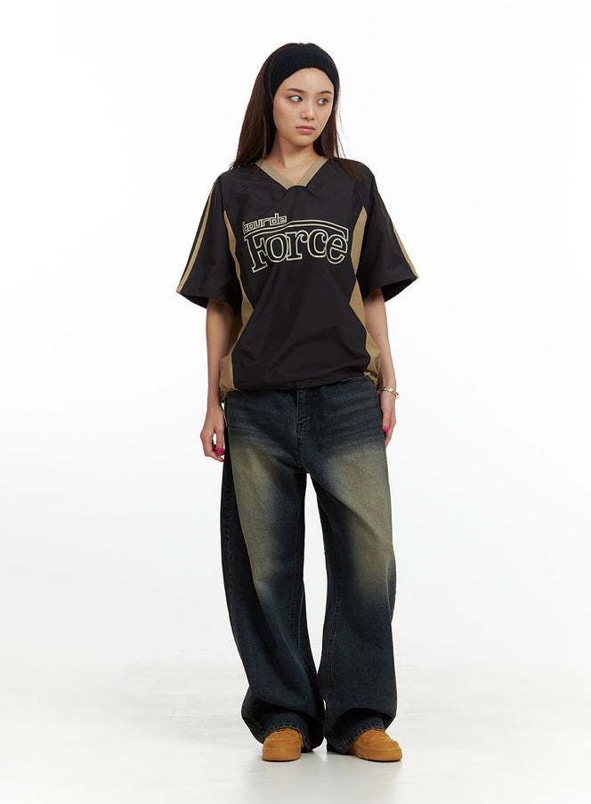 Solid Low Rise Baggy Jeans CU417 in dark blue, full-body front shot on model, wide-fit washed denim with yellow fade highlights, paired with black graphic jersey top and tan sneakers.