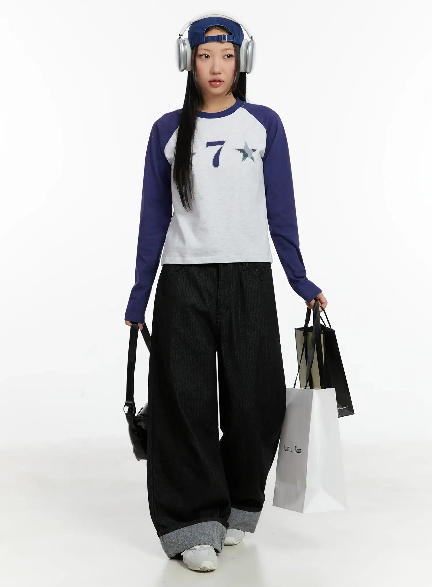 Amyra Baggy Striped Jeans ID525 in black, full-body front editorial shot on model wearing headphones, paired with white and navy raglan top, shopping bags, street style.