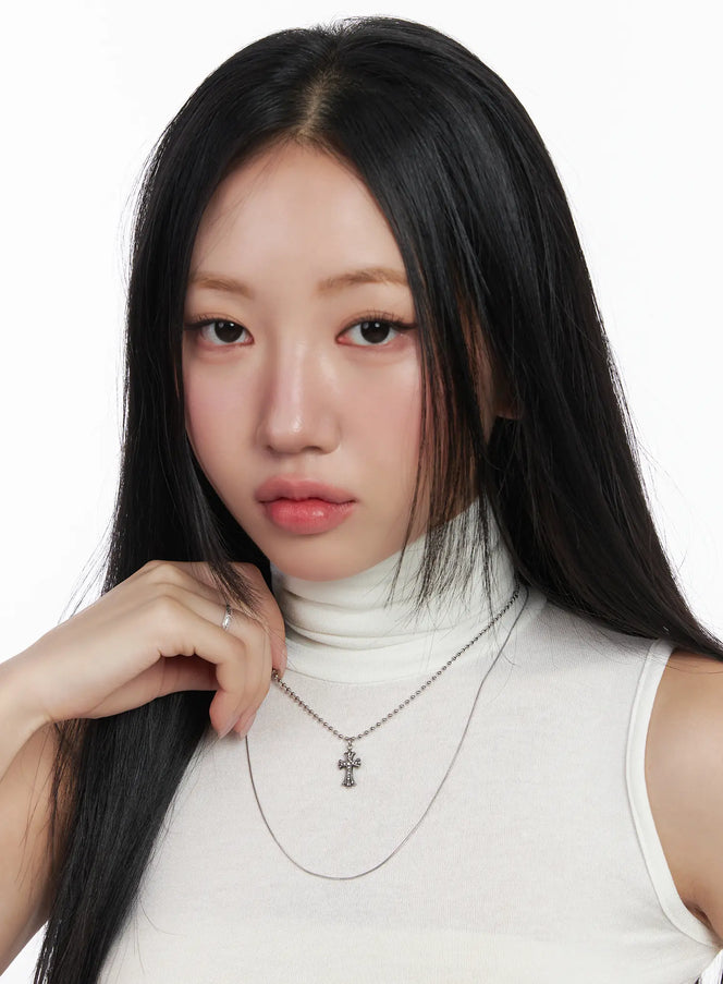 Layered Geometric Pendant Necklace CD530 in silver, front portrait on model, layered ball chain cross pendant and thin snake chain, worn with white sleeveless turtleneck.