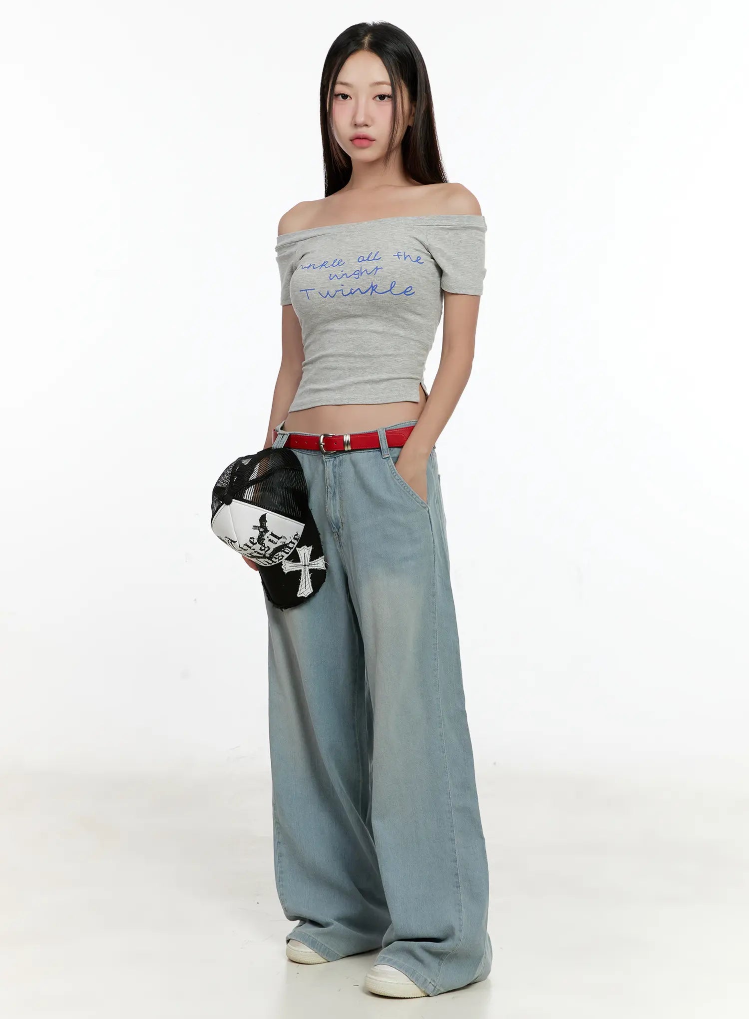 Huening Wide-Leg Jeans CL531 in blue, full-body front shot on model standing with cap in hand, low-rise washed wide-leg denim styled with grey off-shoulder crop top and red belt.