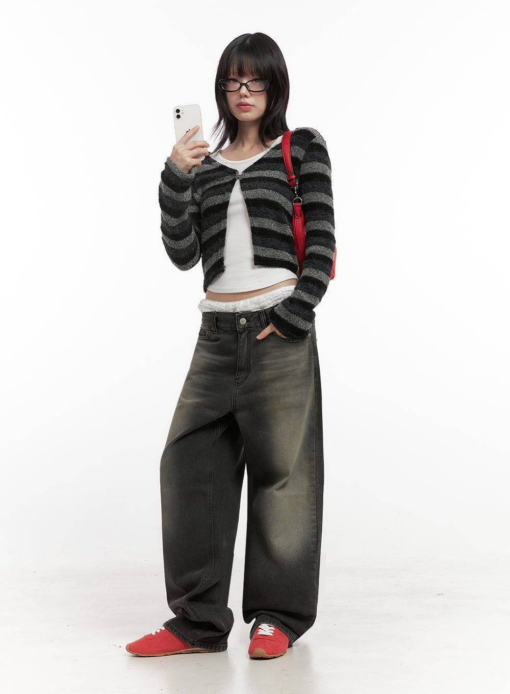 Matilda Wide-Fit Baggy Jeans ID402 in black, full-body front shot on model holding phone, extra-wide washed denim leg, paired with striped crop cardigan and red crossbody bag.