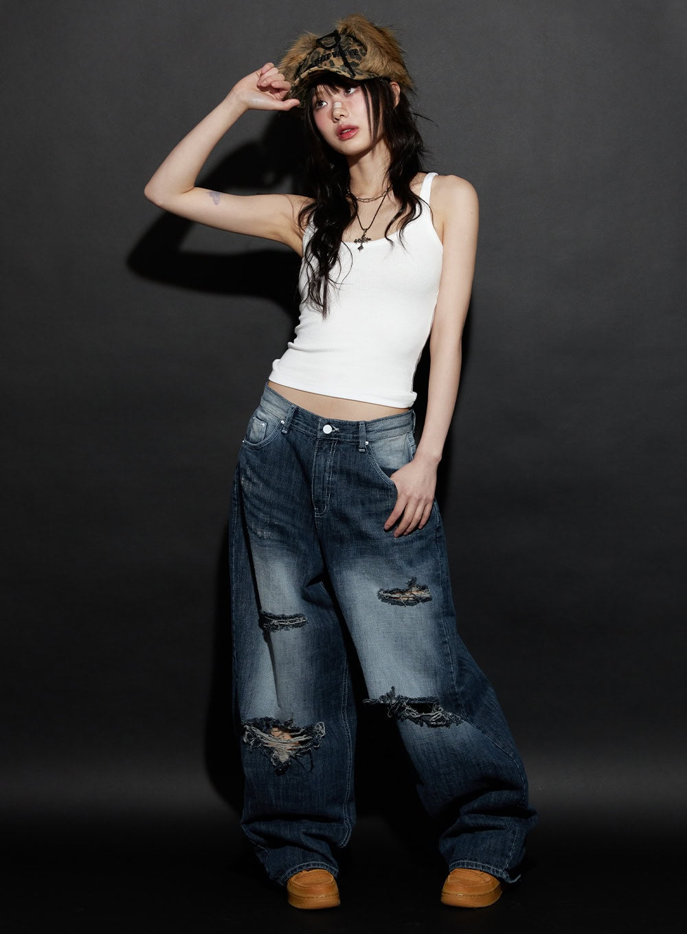 Alison Destroyed Baggy Jeans CJ523 in dark blue, full-body editorial shot on model with fur bucket hat and white tank, wide-leg silhouette with multi-rip destroyed details.