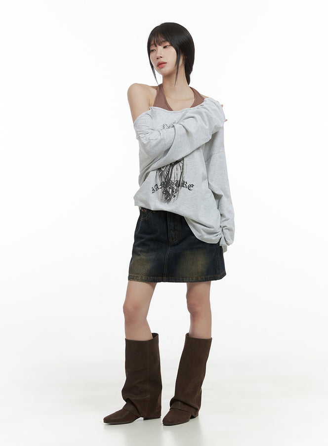 Washed Cotton Mini Skirt CS419 in dark blue, full front shot on model, washed denim mini with golden fade, paired with oversized graphic sweatshirt and brown tall boots.